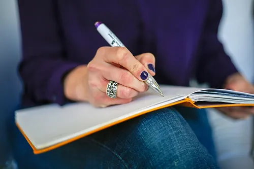 Woman writing on a notebook with a pen